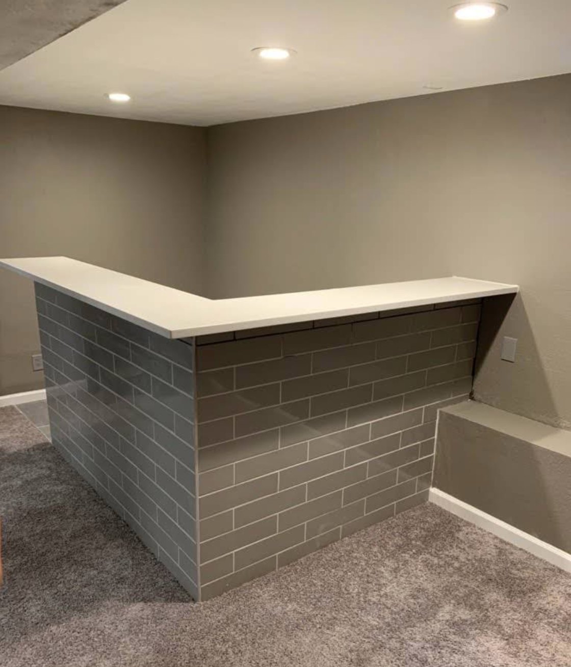 Tiled basement bar with a white countertop