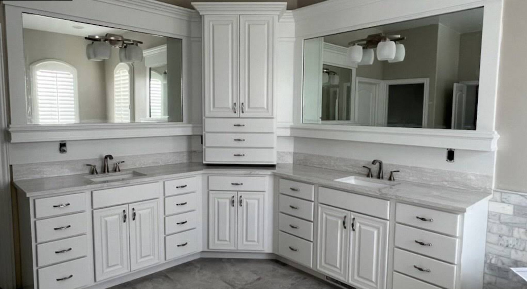 Corner double vanity with white cabinetry and framed mirrors