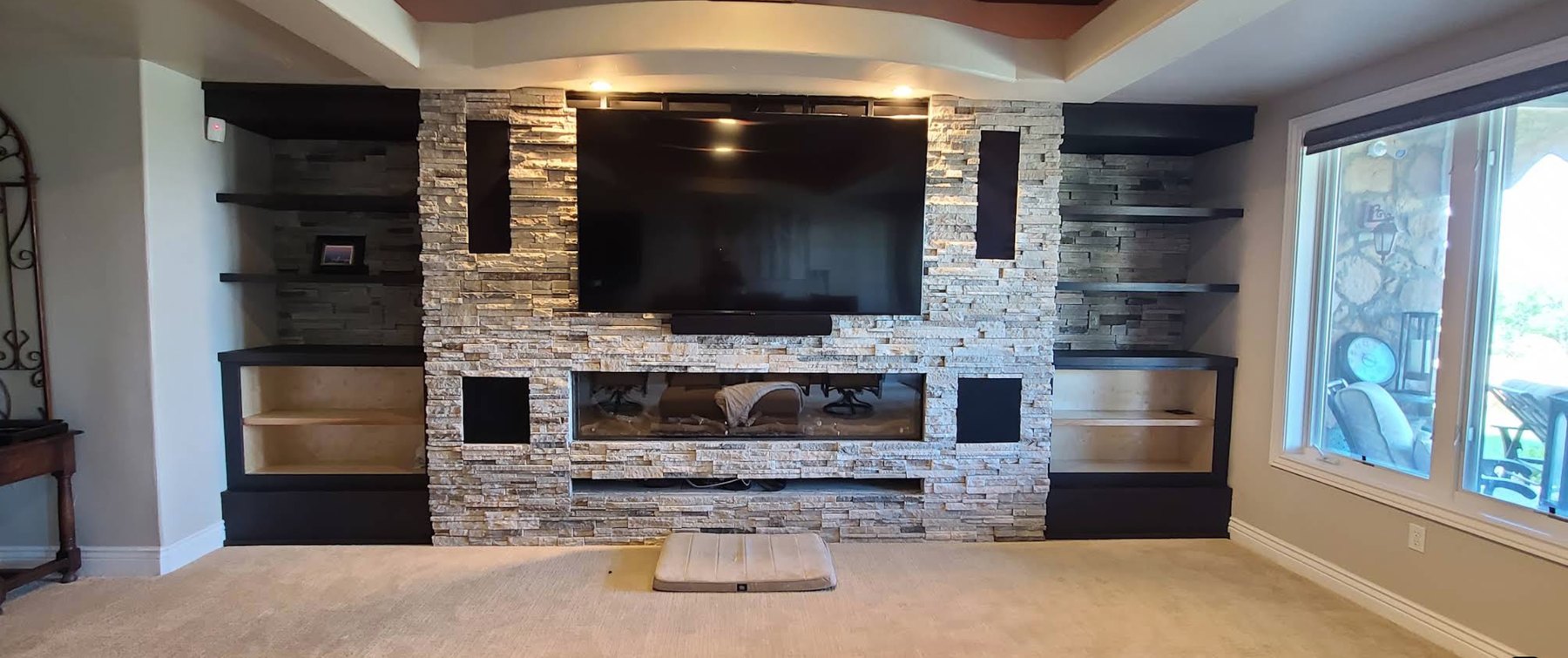 Stacked-stone entertainment wall with linear fireplace and built-ins