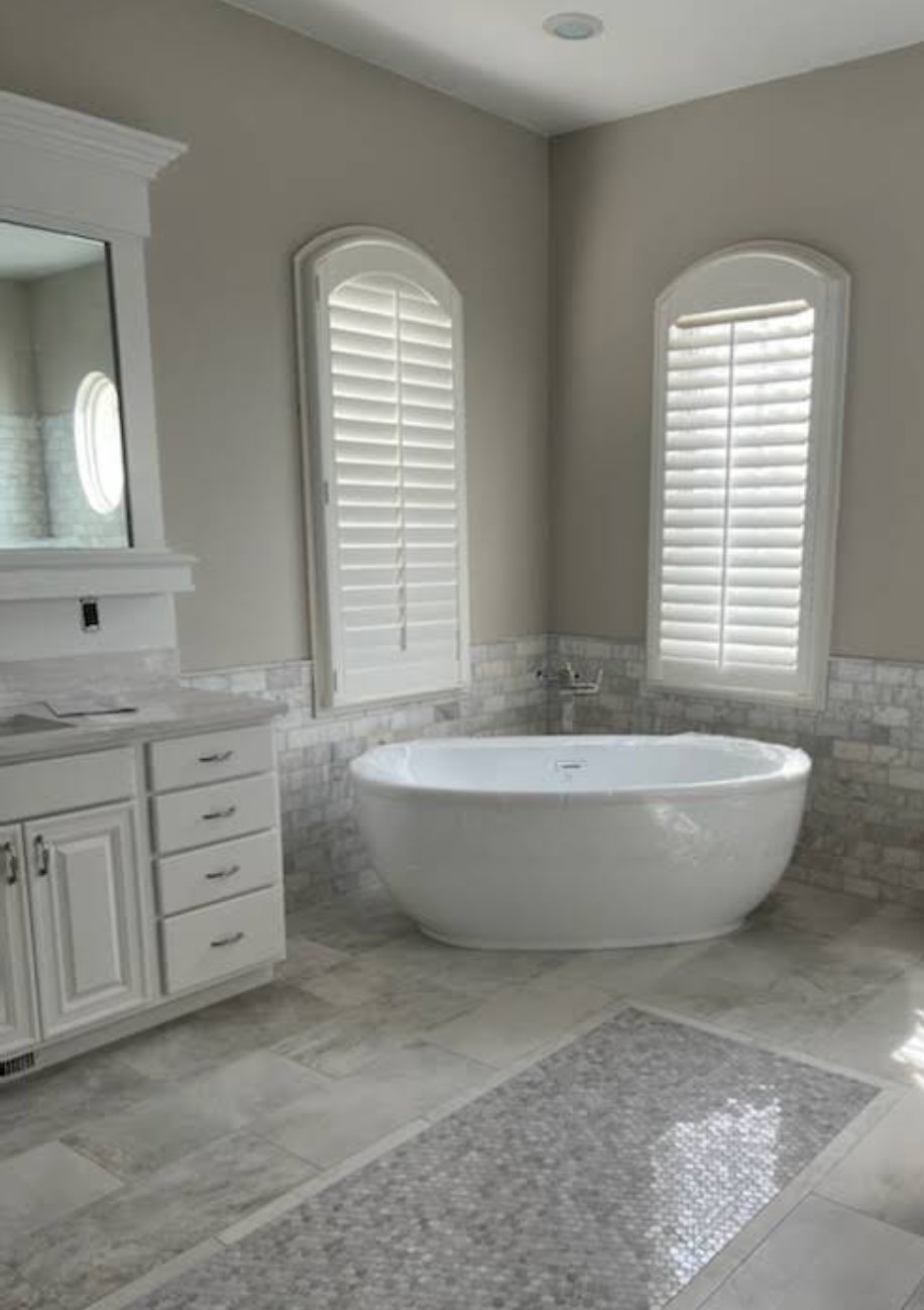 Remodelled master bath with freestanding tub and marble tile