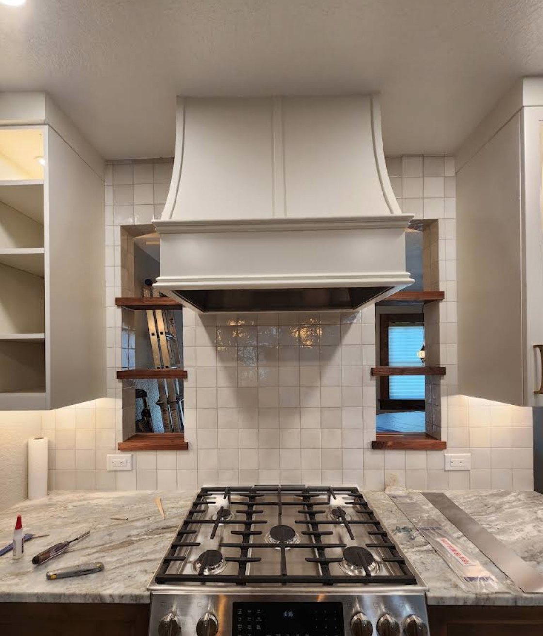 Custom range hood surround with walnut niche shelves