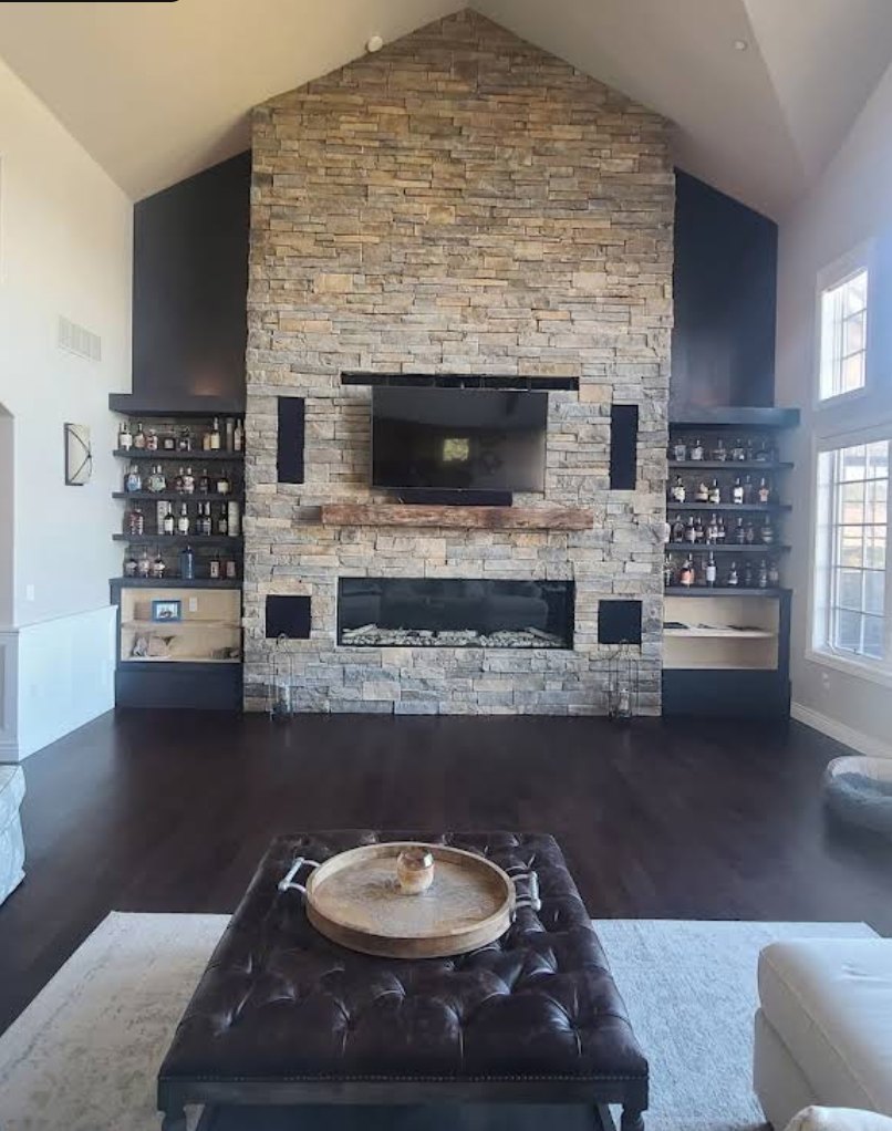 Stone fireplace flanked by black built-in shelving