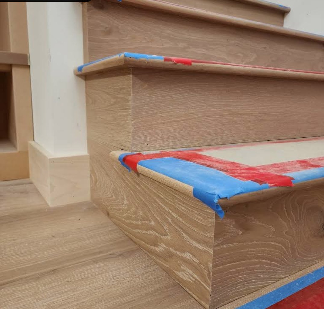 White oak stair treads and risers with painter's tape protecting the nosing